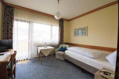 a bedroom with a bed and a couch and a television at Hotel Weidenau in Bad Orb