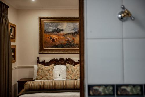 a bedroom with a bed with a painting on the wall at Kleine Constantia Boutique Guest House in Roodepoort