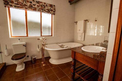 a bathroom with a tub and a toilet and a sink at Kleine Constantia Boutique Guest House in Roodepoort