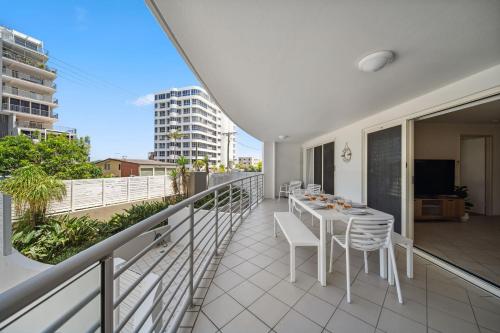 a balcony with a table and chairs on it at Windsong Caloundra Sunsets Sea Breezes and Style in Caloundra