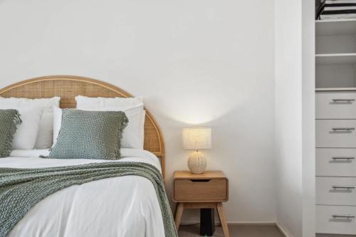 a bedroom with a bed and a table with a lamp at Windsong Caloundra Sunsets Sea Breezes and Style in Caloundra