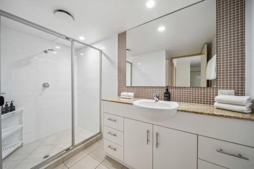 a white bathroom with a sink and a shower at Windsong Caloundra Sunsets Sea Breezes and Style in Caloundra