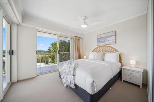 a bedroom with a bed and a large window at Windsong Caloundra Sunsets Sea Breezes and Style in Caloundra