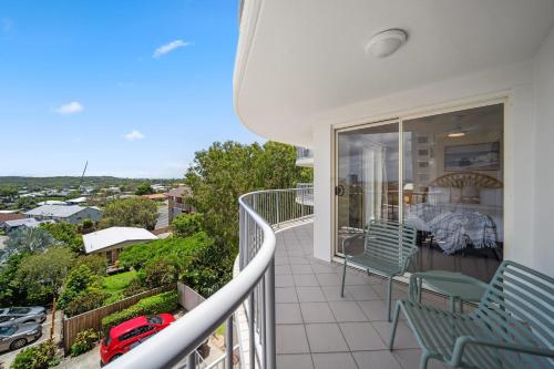 a balcony with green chairs and a view of the city at Windsong Caloundra Sunsets Sea Breezes and Style in Caloundra