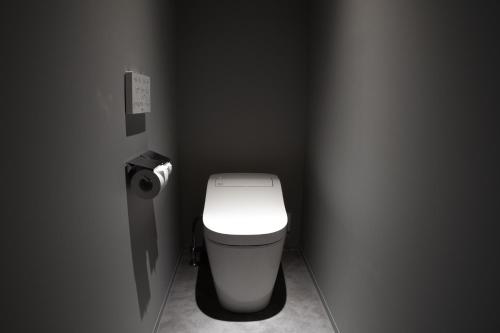 a bathroom with a white toilet in a gray room at UNPLAN Residence suite in Chikuni