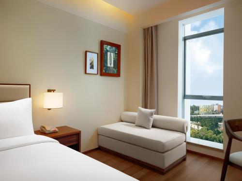 a hotel room with a bed and a chair and a window at Model J Hotel Jakarta Soekarno - Hatta Airport 曼居酒店 雅加达苏加诺哈达机场店 in Gardu