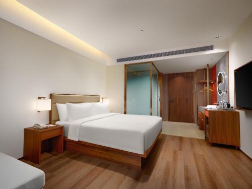a bedroom with a white bed and a television at Model J Hotel Jakarta Soekarno - Hatta Airport 曼居酒店 雅加达苏加诺哈达机场店 in Gardu