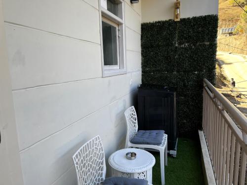 a porch with two chairs and a table and a window at Solan Woods - Cozy Studio Apartment in Chester Hills, Solan in Solan