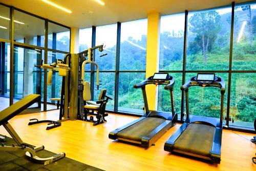 a gym with two tread machines in a room with windows at Solan Woods - Cozy Studio Apartment in Chester Hills, Solan in Solan