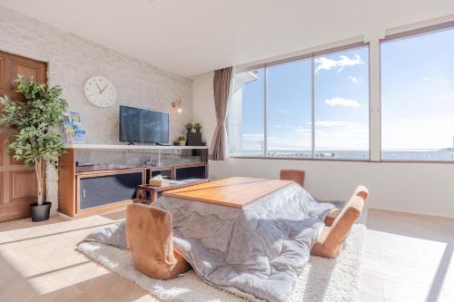a living room with a table and large windows at Sea View Villa Atami in Atami