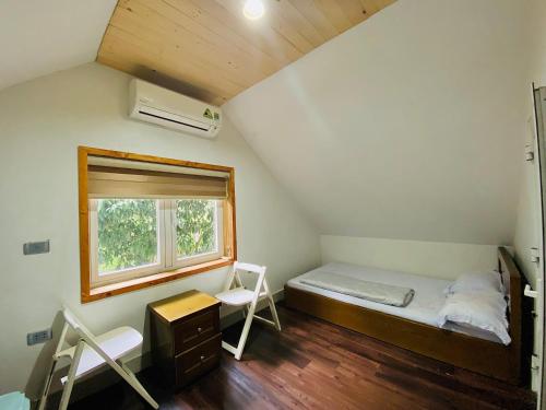 a small room with a bed and a window at Nhà gác mái ven rừng gần Sân bay Nội Bài - Biệt thự con công in Sóc Sơn