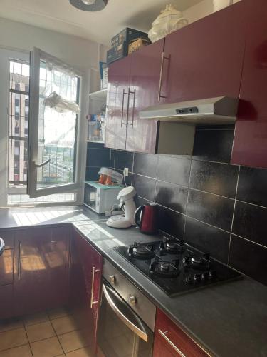- une cuisine avec des placards violets et un four avec plaques de cuisson dans l'établissement Appartement familial à Sarcelles de 81 m², proche commodités, à Sarcelles