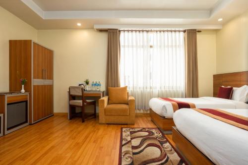 a hotel room with two beds and a desk at Magnificent Hotel in Kathmandu