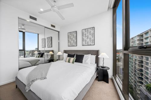 a white bedroom with two beds and a large window at Capri Apartments - Free Secure Parking in Brisbane