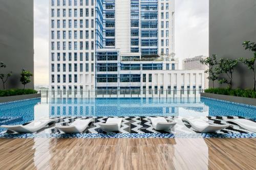 a pool with white lounge chairs in front of a building at Alinea Luxury Condominiums, Shah Alam - Smarthome in Shah Alam