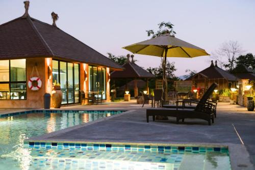 a pool with a chair and an umbrella next to a building at Katiliya Park Villa in Mae Chan