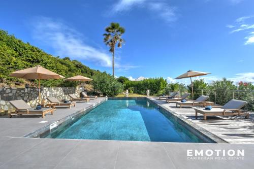 a swimming pool with lounge chairs and umbrellas at New Seaside Elegance Luxury Villa in Oyster Pond - December 2024 renovated in Oyster Pond