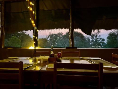 a table in a restaurant with a view of a window at Bwana Tembo Safari Camp in Paraa