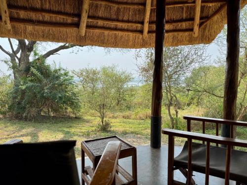 a room with a table and chairs and a view of a field at Bwana Tembo Safari Camp in Paraa