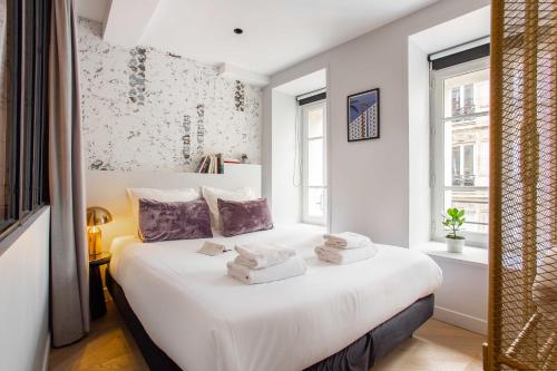 une chambre avec un lit blanc avec des serviettes dessus dans l'établissement Résidence Caire - Paris center, à Paris