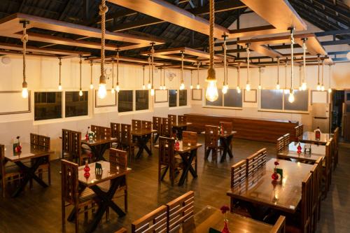 a restaurant with wooden tables and chairs and lights at jungle view resort in Mananthavady