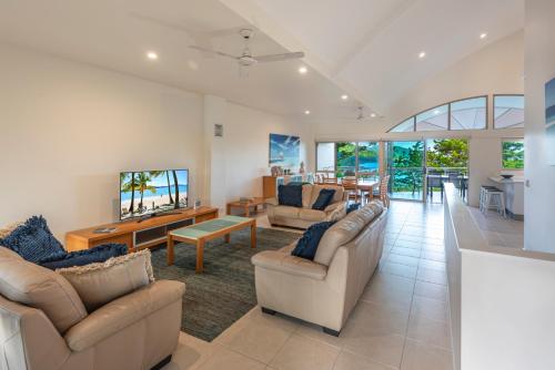 a living room with two couches and a television at Cooinda Gardens on Hamilton Island by HIHA in Hamilton Island