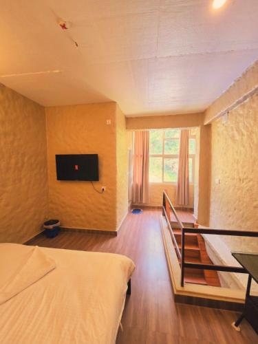 Habitación con cama y TV en la pared. en Nishan Apartments -Lakeside, en Pokhara
