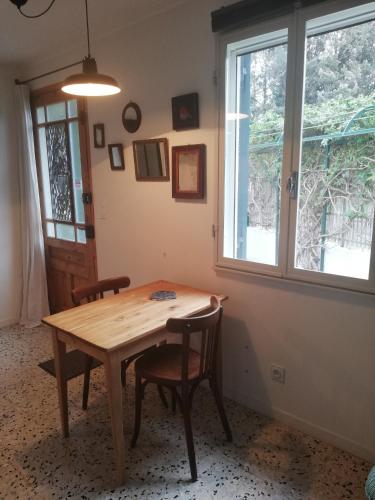 - une table et des chaises en bois dans une chambre avec fenêtre dans l'établissement Gîte de la treille, à LʼIsle-sur-la-Sorgue