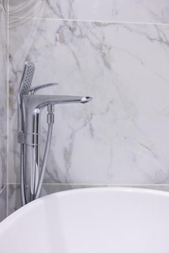 a bath tub with a shower head in a bathroom at Spacious and Premium 2 Bedroom Apartment with Panoramic Terrace and Rudaki Park View in Prime Dushanbe Location in Dushanbe