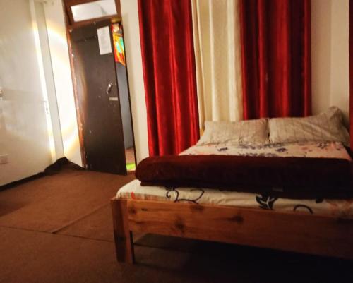 カリンポンにあるHeaven Valley Homestayの赤いカーテンが備わる客室のベッド1台