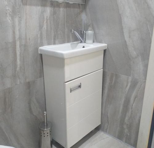 a bathroom with a white sink and a wall at Apartman Marina Aranđelovac in Arandjelovac