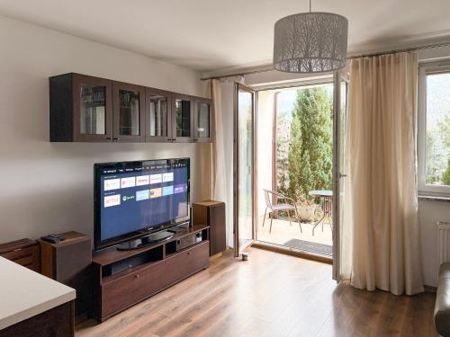 salon z telewizorem i przesuwnymi szklanymi drzwiami w obiekcie APARTAMENT POD GWIAZDAMI, z dwoma ogródkami i dwoma tarasami w Polanicy Zdroju