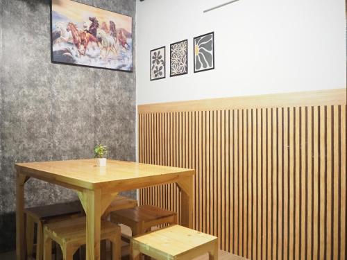 a wooden table and benches in a room with a wall at Bed Space Hostel Khaosan in Bangkok