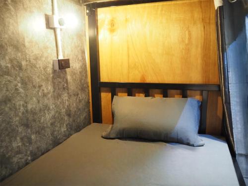 a bed with a wooden headboard and a white pillow at Bed Space Hostel Khaosan in Bangkok