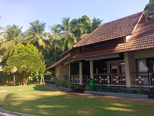 a house with palm trees in the background at Bharathapuzha resort in Kārakkād