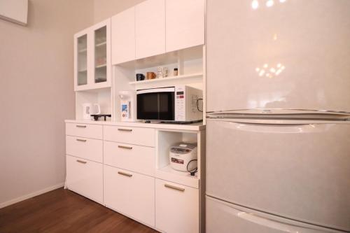 a kitchen with a refrigerator and a microwave at デコピンハウス in Hanamaki