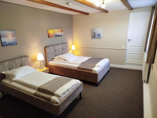 two beds in a hotel room with two lamps at B&B Dumbrava in Gura Humorului