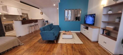 un salon avec une chaise bleue et une télévision dans l'établissement Le Petit Loft de Saint Herem, à Clermont-Ferrand