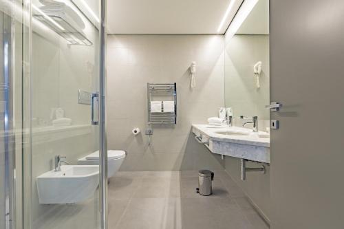 a bathroom with two sinks and a toilet and a shower at Just Hotel Saronno in Saronno