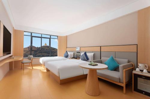 Un dormitorio con una cama, un sofá y un televisor. en Days Hotel by Wyndham Aba Hongyuan, en Hongyuan