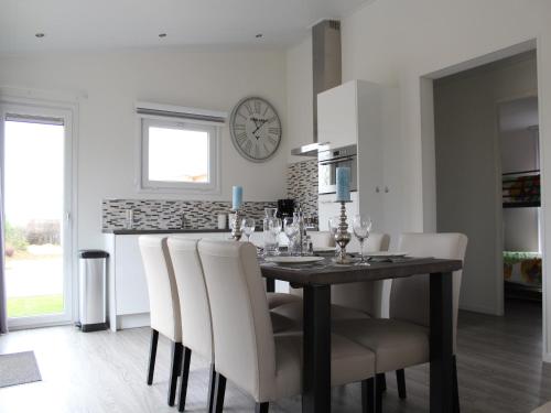 a dining room table with white chairs and a clock on the wall at Stylish Villa in Bemelen in Bemelen