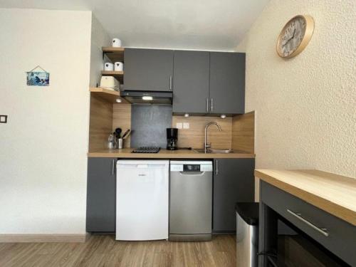 une cuisine avec des armoires grises et un réfrigérateur blanc dans l'établissement Résidence Hameau Thermes Ii - HAMEAU DES THERMES 4 personnes à deux pas des Thermes et Télécabine MAE-4541, à Saint-Lary-Soulan