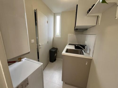 - une petite cuisine blanche avec un évier et un comptoir dans l'établissement Studio rénové proche Rives de l'Orne et gare, à Caen