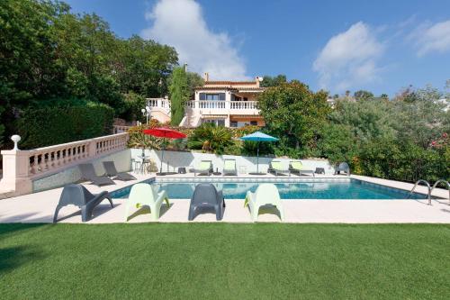 une piscine avec des chaises et une maison en arrière-plan dans l'établissement Jolie bastide 5 chambres avec belle vue mer, à Mandelieu-la-Napoule
