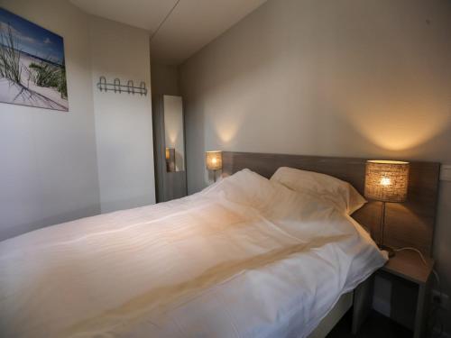 a bedroom with a large white bed with two lamps at Chalet on the recreational lake and the Veluwe in Lathum