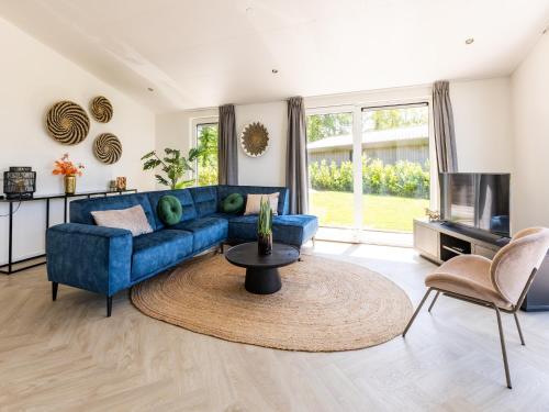 a living room with a blue couch and a table at Chalet by Pond in Holiday Park in Veldhoven