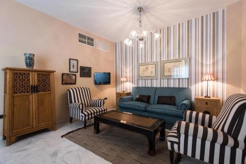 a living room with a blue couch and two chairs at Singular Corral de San José in Seville