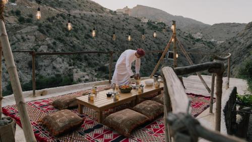 a man standing next to a table on a mountain at the suwgra-Al-Jabal Al-Akdar in Sūkirah