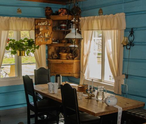 a dining room with a wooden table and some windows at Kvebergsøya Gard in Grimsbu