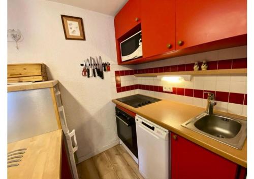 - une petite cuisine avec un évier et des placards rouges dans l'établissement Résidence Doronic - Résidence DORONIC N°861 MAE-4931, à La Plagne Tarentaise